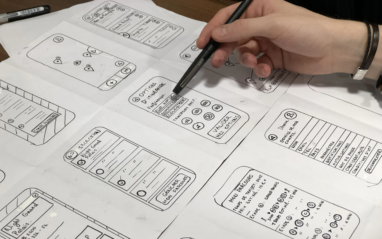 Person holding pen near paper wireframes