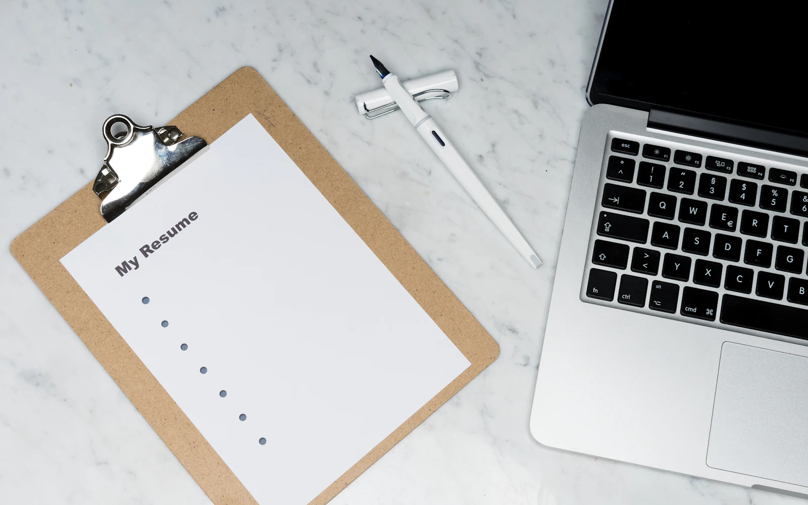 Printed resume pages beside a laptop