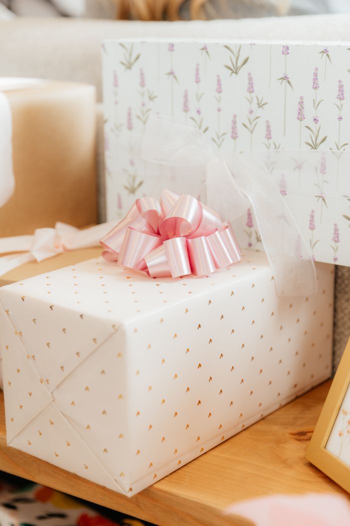 Keepsake gift box wrapped in paper printed with tiny gold motifs and topped with a pink satin pull-bow.