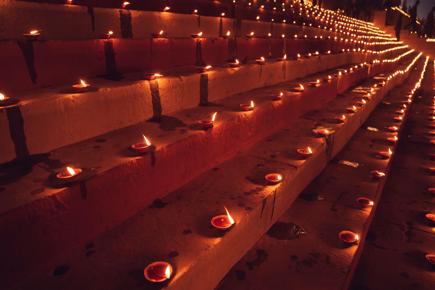 Rows of small clay lamps burning along stone steps at night, converging toward the distance.