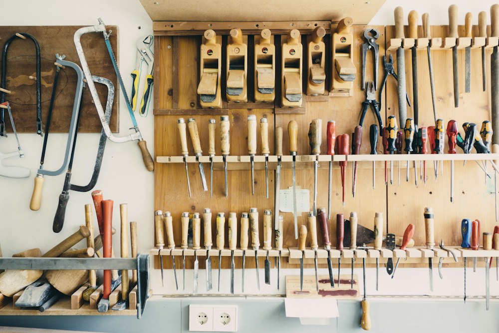 A wooden tool wall with hand planes, chisels, screwdrivers, saws and pliers hung in tidy rows.