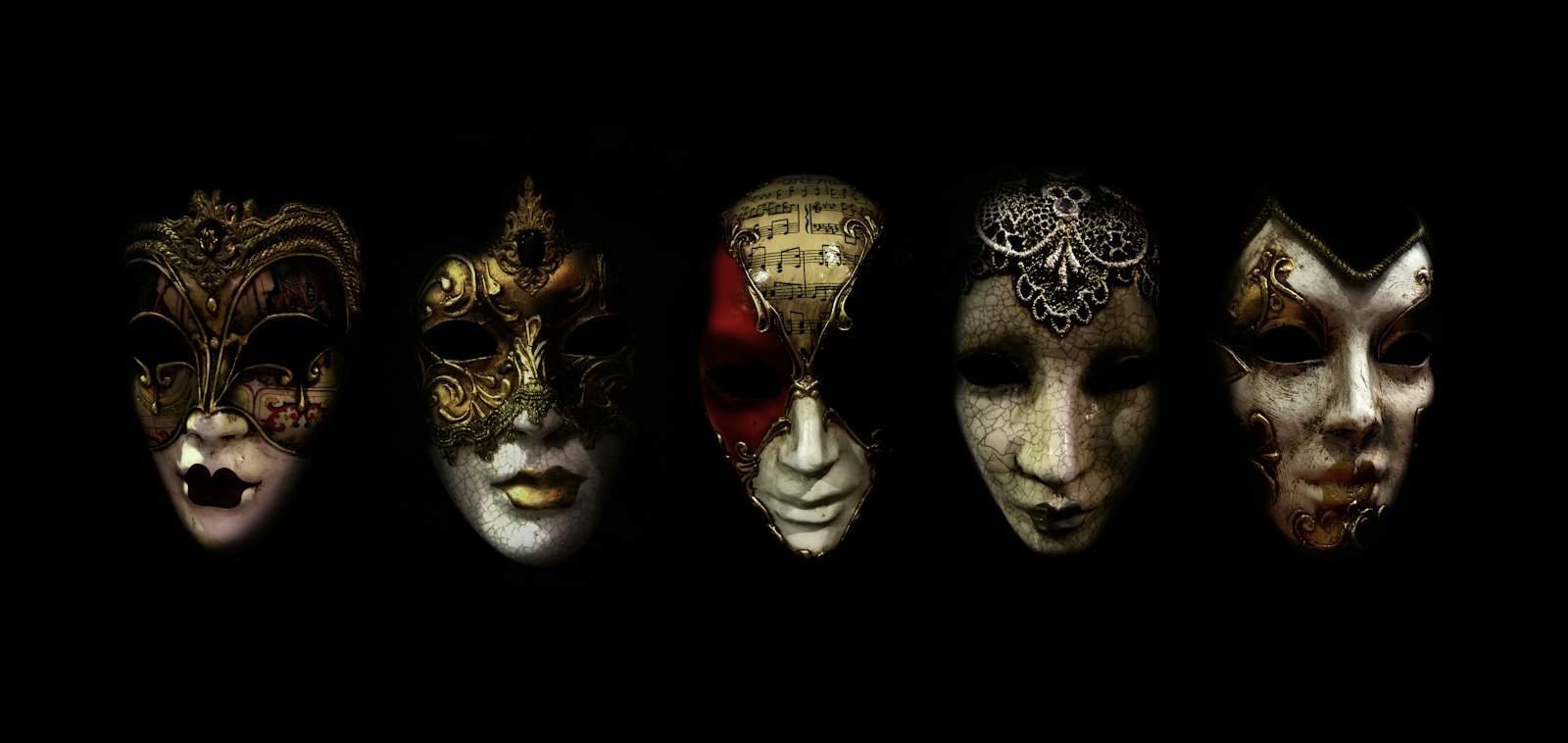 Five Venetian masks in black, gold, red and ivory arranged in a row against a black background.
