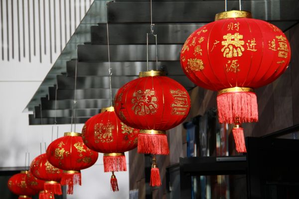 Red Chinese lanterns with gold symbols hanging in front of a building.