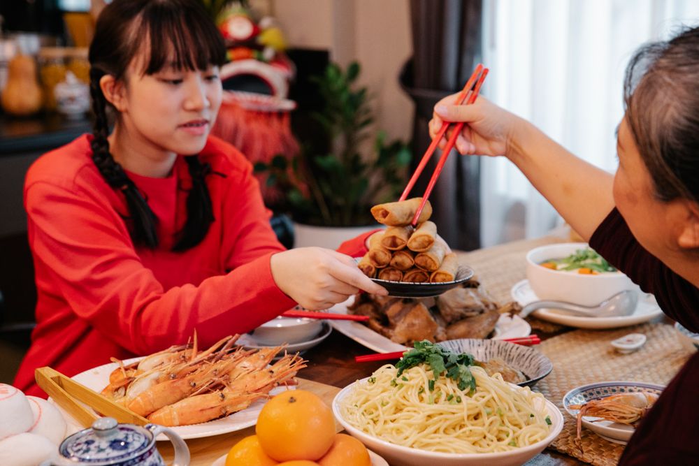 A family gathered around a table sharing a traditional Lunar New Year meal.