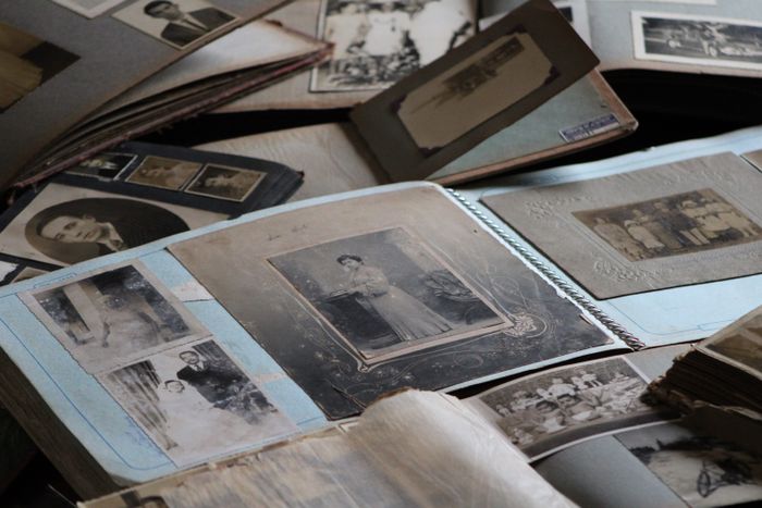 Open vintage photo albums and loose black-and-white family portraits scattered across a table