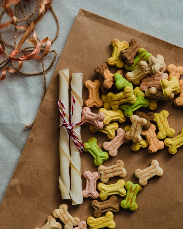 Bone-shaped dog treats arranged on brown paper, seen from above.